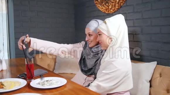 两个穆斯林妇女坐在餐厅的桌子旁自拍视频的预览图