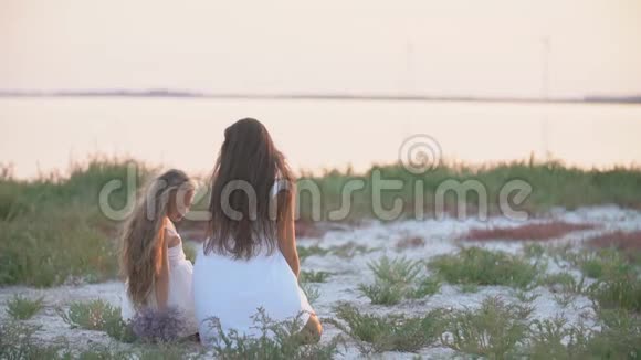 妈妈和女儿坐在沙滩上眺望远方视频的预览图