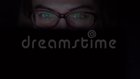 戴眼镜的女孩晚上用笔记本电脑躺在家里的床上孤立光视频的预览图