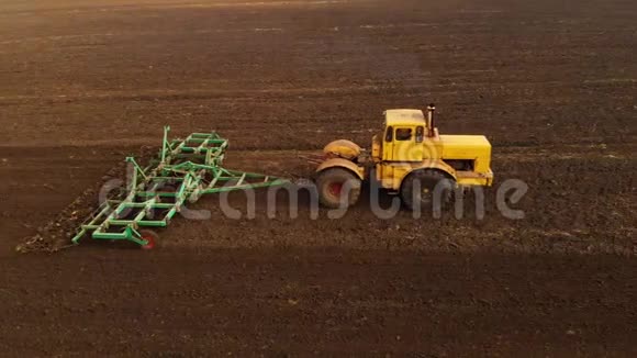 一辆黄色拖拉机的鸟瞰图拖车在种植谷物之前在耕地上犁地这就是视频的预览图