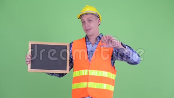 一位年轻的建筑工人扶着黑板竖起大拇指视频的预览图