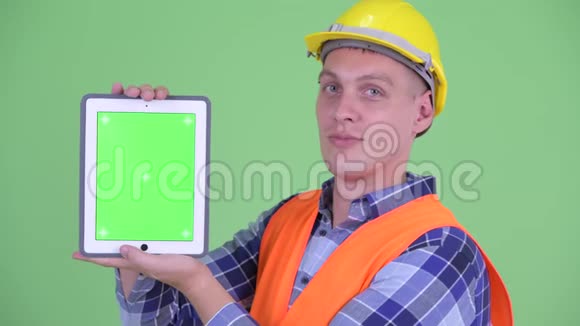 青年建筑工人展示数码平板电脑的脸视频的预览图