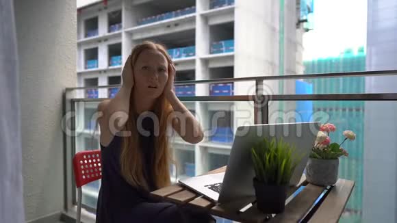 一名年轻女子坐在阳台上拿着笔记本被一个人发出的一声巨响击中视频的预览图