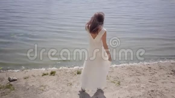 一位美丽的少女一头深色长发穿着一件白色的夏装站在河边视频的预览图