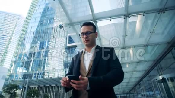 拥有智能手机的迷人商人正站在商业摩天大楼附近视频的预览图