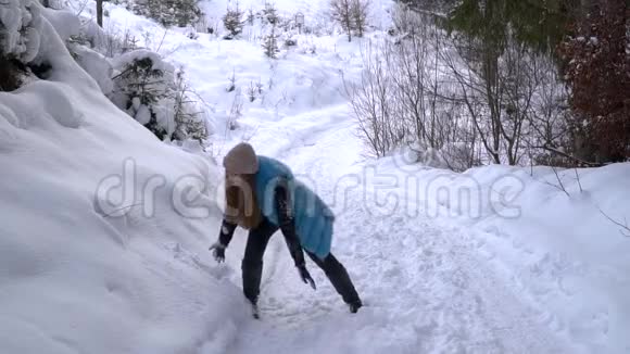 年轻漂亮的女孩在冬天的森林里玩她高兴地扔雪和弹跳女孩很快乐视频的预览图