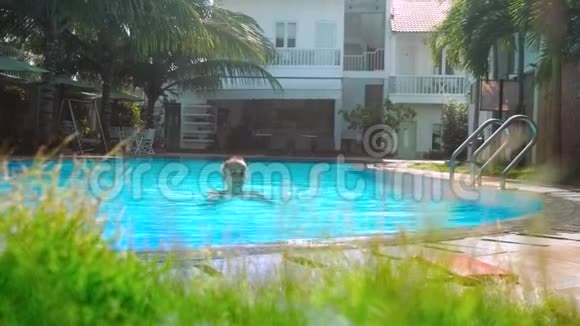 女孩游过酒店游泳池到棕榈树之间的障碍视频的预览图
