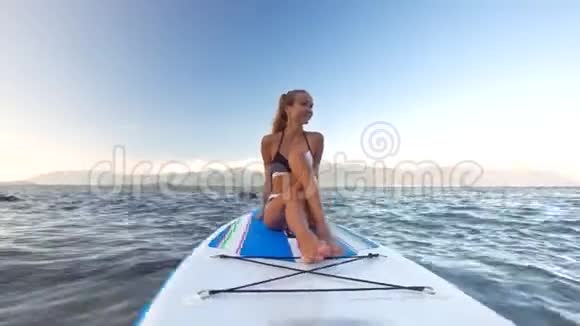 在海洋中坐在桨板上的女孩身上视频的预览图