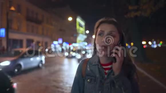魅力十足的女人在智能手机上说话穿过城市的街道视频的预览图