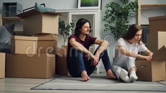 女孩和男孩在搬迁期间拆包从盒子里拿东西说话视频的预览图