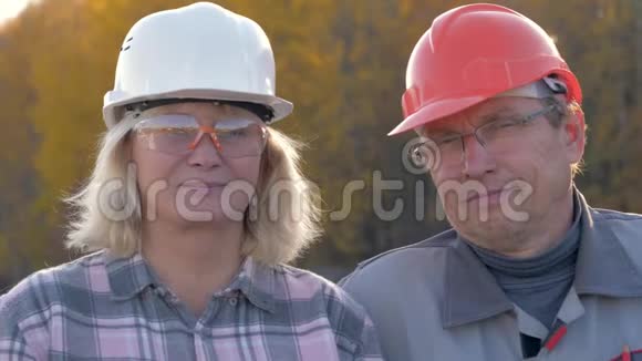 建筑工人戴着头盔看镜头的男人和女人的画像视频的预览图