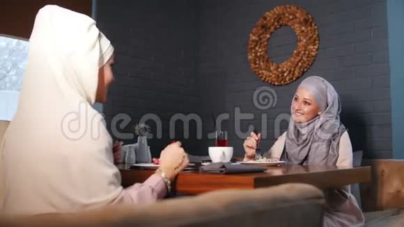 两个穆斯林妇女坐在餐馆里服务员点菜视频的预览图