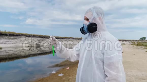 一个穿着防护服和呼吸器的人站在河的背景下手里拿着试管视频的预览图