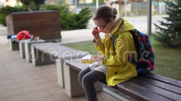孤独的女学生坐在学校附近的长凳上有人经过孩子紧张地擦着眼镜神情视频的预览图