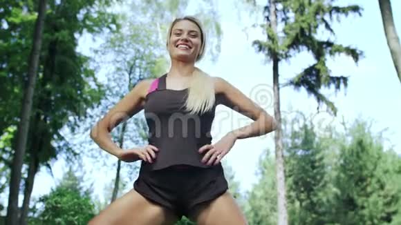 微笑的女人在户外健身前做深蹲运动视频的预览图