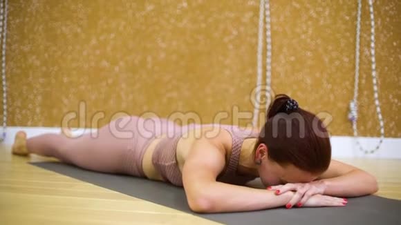 年轻女子躺在垫子上在瑜伽馆做瑜伽练习视频的预览图