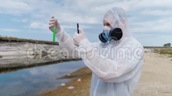 一个穿着防护服和呼吸器的人站在河的背景下手里拿着试管视频的预览图