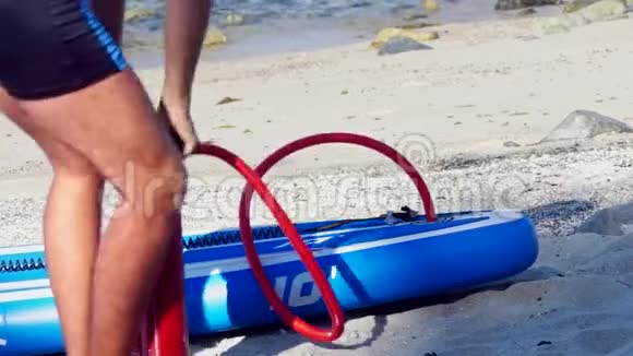 盖伊在海滩上缓慢地划桨低角度拍摄视频的预览图