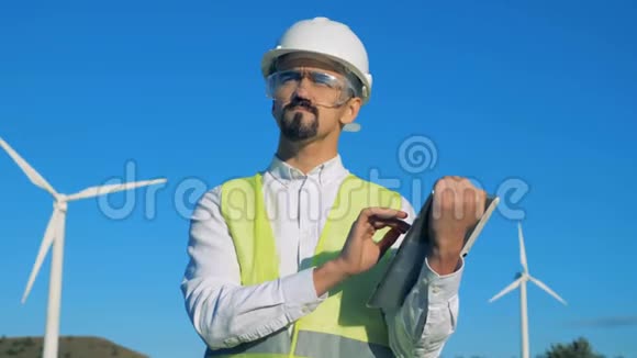 男工正在操作平板电脑而站在涡轮塔旁边清洁环保的能源理念视频的预览图