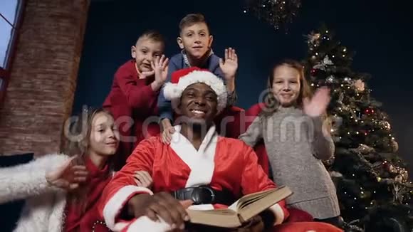 快乐的圣诞老人戴着红帽子可爱的四个孩子向相机挥手视频的预览图