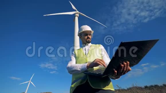 当技术人员操作笔记本电脑时风力涡轮机正在旋转清洁环保的能源理念视频的预览图