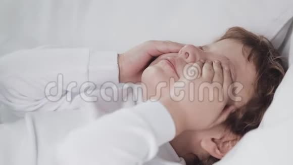 在家里的床上哭着的小男孩一个牙齿上有龋齿的四岁男孩哭了慢动作视频的预览图