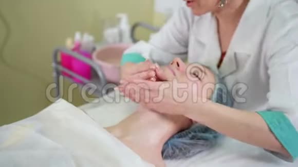 美容诊所面部按摩治疗一位女性美容师轻轻按摩女性的下巴视频的预览图
