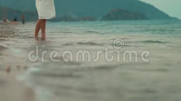 日落时在海边的女性腿站在海浪中的少女视频的预览图
