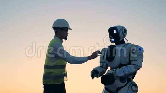日落景观一个机器人由一名男性技术员控制视频的预览图