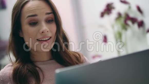 幸福的女人笑着看着家里的笔记本电脑女孩在线视频通话视频的预览图