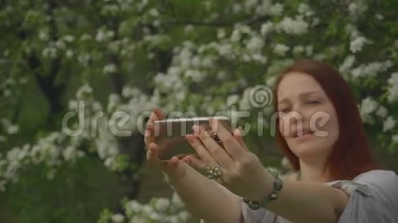 生活方式的女人在盛开的花园里打电话自拍视频的预览图