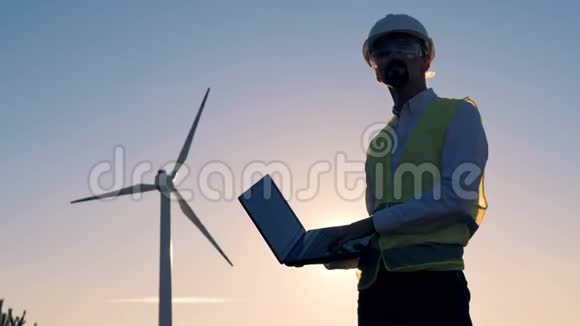 当一位能量学专家正在观察风车时太阳正在下山清洁环保的能源理念视频的预览图