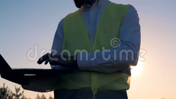 关闭一台笔记本电脑在一个男性工人手中站在涡轮塔附近清洁环保的能源理念视频的预览图