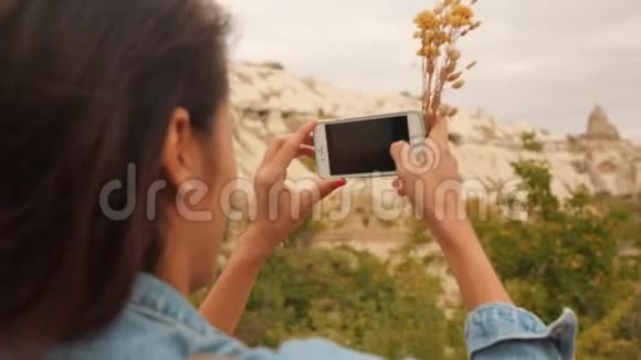 年轻的混合种族旅游女孩拍摄美丽的山岩使用手机在卡帕多西亚土耳其4K慢动作视频的预览图