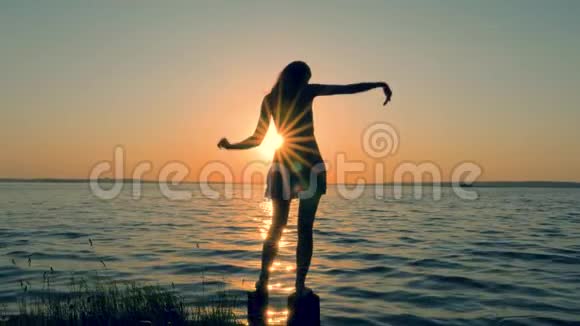 美丽的女人穿着礼服在金色夕阳下的沙滩上跳舞视频的预览图