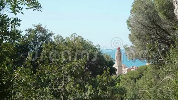 通过绿树观赏西班牙小镇卡拉拉及其建筑和教堂背景上的绿松石海视频的预览图