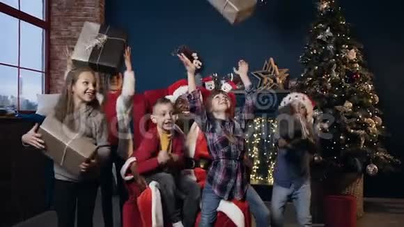 快乐的孩子们喜欢圣诞老人送的礼物在圣诞树的背景上呕吐和微笑视频的预览图