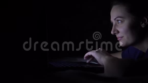 迷人的快乐女人在晚上躺在床上在笔记本电脑键盘上打字孤立光视频的预览图