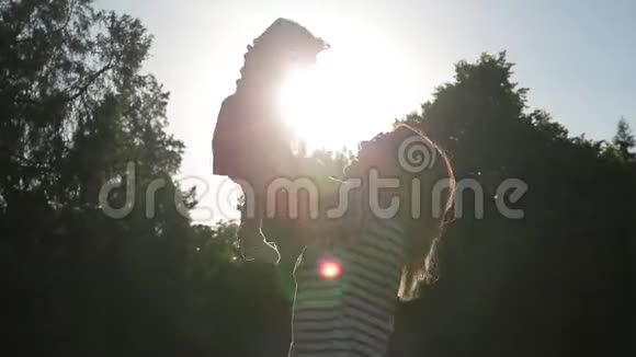 低角度拍摄年轻可爱的妈妈把她的小女儿抱在怀里然后在明亮的阳光下拥抱她视频的预览图