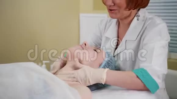 美容诊所的按摩治疗医生在病人脸上涂奶油视频的预览图