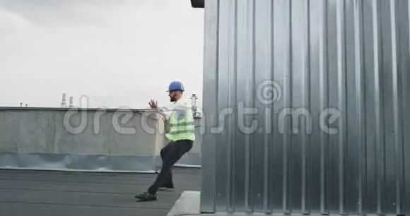 建筑工地的屋顶上戴着安全帽的漂亮男人工程师或建筑师在兴奋地跳舞视频的预览图