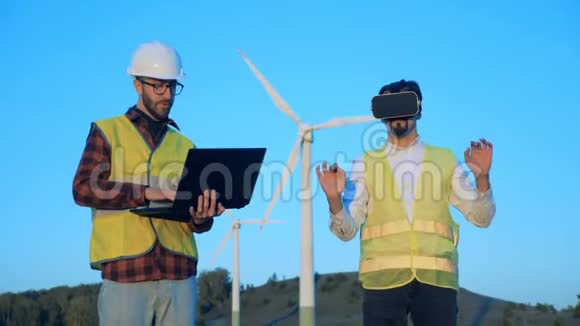 两名技术人员正在用笔记本电脑和虚拟眼镜控制风力涡轮机清洁环保的能源理念视频的预览图