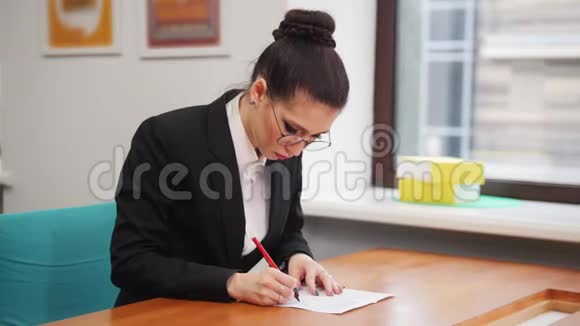 商业概念一个戴眼镜的女人坐在桌子旁把文件装满视频的预览图