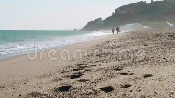 冲破海浪无法辨认的人在海上行走前景上的湿沙迹视频的预览图