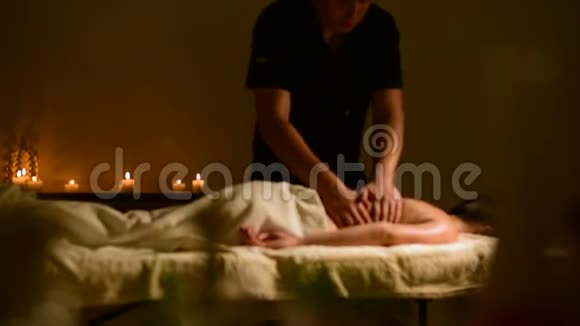 特写水疗按摩妇女肩膀和背部男人的手在黑暗的房间里给女人按摩里面有蜡烛视频的预览图