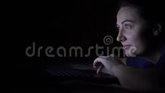 迷人的年轻快乐的女人在晚上躺在床上时使用移动电脑孤立光视频的预览图