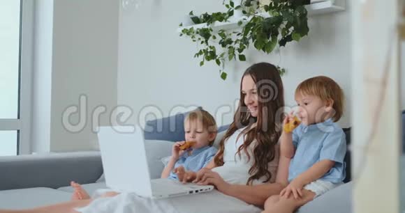 一位年轻的母亲和两个年轻的儿子用笔记本电脑在网上商店购物视频的预览图
