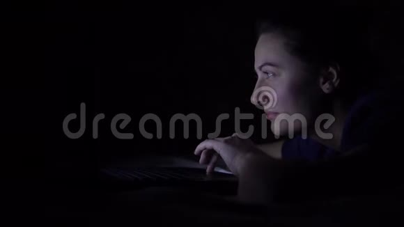 迷人的快乐女人在晚上躺在床上时使用移动电脑隔离灯4K视频的预览图