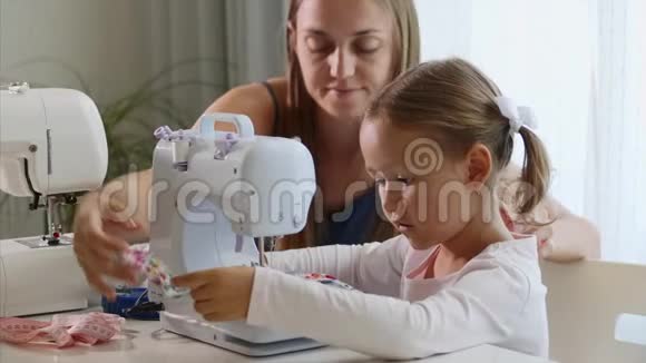 一个女孩在机器上缝纫妈妈展示如何使用设备特写镜头视频的预览图