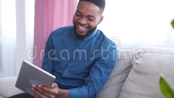 沙发上用数码平板电脑的快乐男人视频的预览图